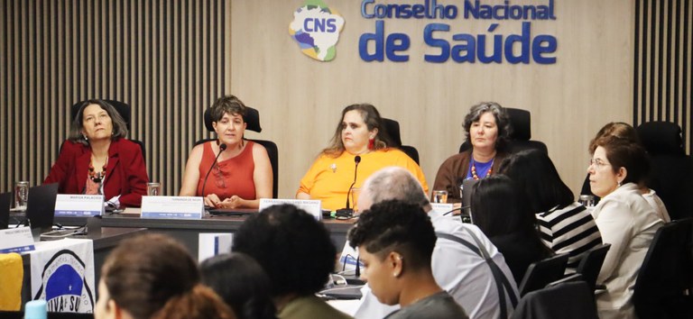 Mesa principal com todas as participantes sentadas olhando para o plenário