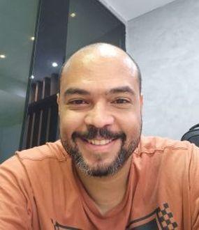 Homem pardo, careca, vestindo camiseta laranja
