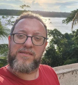 Homem de barba e óculos, vestindo uma camisa vermelha
