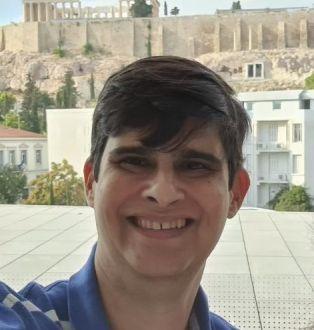 Homem branco, cabelos lisos, vestindo camisa azul, com listras horizontais brancas